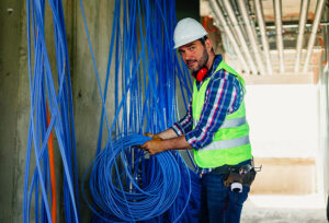 Photo of a construction worker installing lots of blue backbone cabling for a multi-story commercial building